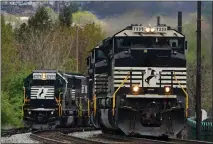  ?? GENE J. PUSKAR — THE ASSOCIATED PRESS ?? A Norfolk Southern freight train passes a train on a siding as it approaches a crossing in Homestead, Pa., on April 27. Freight railroads and their unions are facing increasing pressure from business groups and the White House to settle their contract dispute.