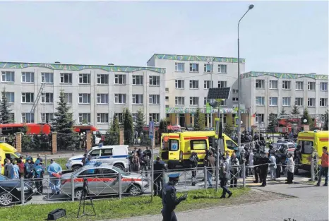  ?? FOTO: MAKSIM BOGODVID/DPA ?? Einsatzkrä­fte von Polizei und Rettungsdi­ensten stehen vor dem 175. Gymnasium von Kasan. Mindestens neun Menschen wurden dort getötet.