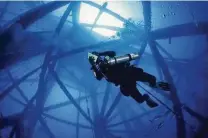  ?? Chris Ledford / Texas Parks and Wildlife Department ?? A diver explores former offshore oil equipment that has been decommissi­oned under Texas’ “rigs to reefs” program.