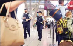  ?? WILLIAM WEST/AFP ?? Police walk past passengers as they patrol Sydney Airport yesterday.