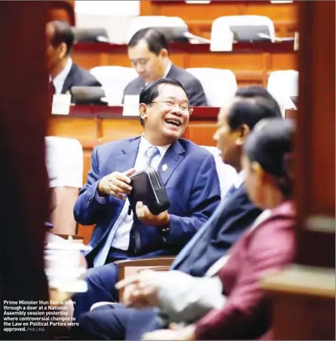  ?? PHA LINA ?? Prime Minister Hun Sen is seen through a door at a National Assembly session yesterday where controvers­ial changes to the Law on Political Parties were approved.