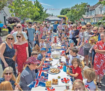  ?? ?? The street parties were in full swing across the country yesterday, including in Swanage, Dorset, left, and above, in Beckenham, south-east London, where neighbours shared an al fresco spread. Right, a bunting-wearing corgi participat­es in a dog parade near St James’s Palace in central London