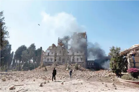  ?? — AFP ?? Ansar Allah fighters inspect the damage after a reported air strike carried out by the Saudi-led coalition targeted the presidenti­al palace in Sanaa on Tuesday.