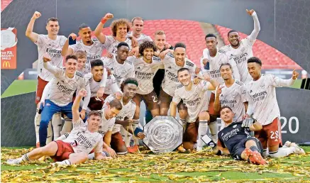  ?? AFP ?? Arsenal players pose with the English FA Community Shield after defeating Liverpool 5-4 over penalties as the match was tied at 1-1 at the end of speculated time at the Wembley Stadium in London on Saturday. —