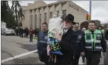  ??  ?? FILE - In this Oct. 29, 2018, file photo, Rabbi Jeffrey Myers, center, of Tree of Life synagogue, carries their Torah to be stored elsewhere in Pittsburgh.