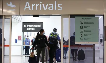  ?? Photograph: Paul Kane/Getty Images ?? Police at Perth airport escort passengers to buses to take them to hotel quarantine. The Australian Human Rights Commission has received ‘a number’ of complaints about the travel cap.