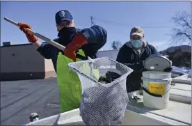  ?? BEN HASTY — READING EAGLE ?? Leo Slogaski, left, and Jake Ketterer, both with the state Fish and Boat Commission, prepare to stock Wyomissing Creek in Cumru Township with trout in February in advance of Saturday’s start of trout season.