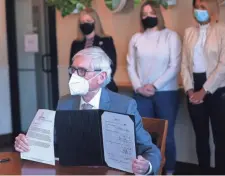  ?? ANGELA PETERSON/ MILWAUKEE JOURNAL SENTINEL ?? Wisconsin Gov. Tony Evers holds up his veto of a Republican bill to control how $3.2 billion in federal stimulus funding is spent Monday at Miss Molly’s Cafe & Pastry Shop at 9201 W. Center St. in Milwaukee.