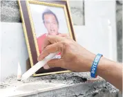  ??  ?? LEFT Rey Almeda wears a Rodrigo Duterte election campaign wristband as he visits the tomb of his brother Michael, who was allegedly killed by the Bonnet Gang, in the town of Pateros.