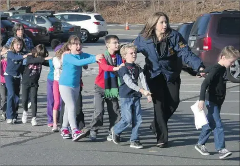  ?? SHANNON HICKS/ NEWTOWN (CONN.) BEE ?? A Connecticu­t State police officer leads a line of children from Sandy Hook Elementary School in Newtown, Conn. after the mass shooting on Friday.