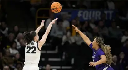  ?? Matthew Putney/Associated Press ?? Iowa guard Caitlin Clark (22) shoots a 3-point basket over Holy Cross guard Simone Foreman in the first half of a first-round college basketball game in the NCAA Tournament, March 23, in Iowa City, Iowa