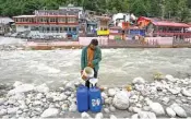  ?? (AFP) ?? A daily wage worker fills cans with meltwater of Gangotri glacier which is the primary source of the pious river Ganges, in Uttarakhan­d