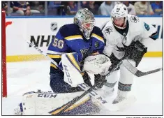  ?? AP/JEFF ROBERSON ?? St. Louis goaltender Jordan Binnington (left) protects the puck as San Jose center Melker Karlsson closes in during the second period of the Blues’ 2-1 victory over the Sharks on Friday night. Binnington made 29 saves in the contest.