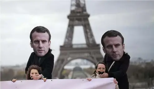 ?? ?? Des militants portant des masques d'Emmanuel Macron placent leurs mains sur des femmes bâillonnée­s lors d'une manifestat­ion à Paris, le 24 novembre 2023.