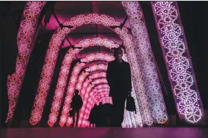  ?? (AP/Kiichiro Sato) ?? People walk through a tunnel of holiday light displays Dec. 9 in Tokyo.