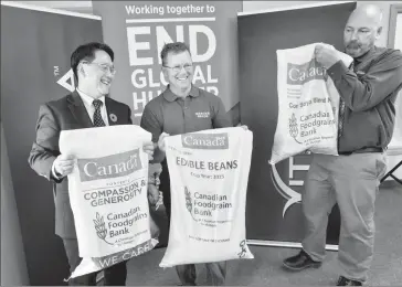  ?? Herald photo by Ian Martens ?? Foodgrains Bank board chair Ken Kim, Mercer Seeds’ Les Bolstad and Viterra’s Davin Lockwood lift grain bags as they pose for photograph­ers as part of a partnershi­p celebratio­n with the Canadian Foodgrains Bank Tuesday at the Lethbridge Viterra Terminal. @IMartensHe­rald