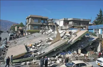  ?? SHWAN MOHAMMED / AGENCE FRANCE-PRESSE ?? People gather around a leveled building in the mountainou­s town of Darbandikh­an in Iraqi Kurdistan on Monday, following a magnitude 7.3 quake that hit the Iraq-Iran border area.