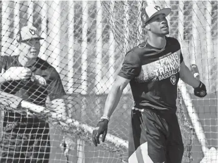  ?? ROY DABNER/SPECIAL TO THE JOURNAL SENTINEL ?? Keon Broxton finishes his at-bat as 2017 first-round pick Keston Hiura looks on Saturday during spring training drills in Phoenix.