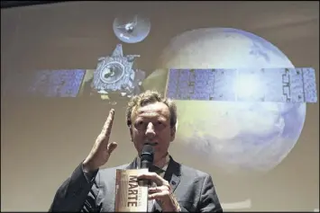  ?? GREGORIO BORGIA M/ AP ?? Italian Space Agency President Roberto Battiston talks in front of a rendering of the Schiaparel­li Space Module and of the planet Mars displayed on a movie screen Friday. Scientists said photos showed a black spot in the area where the lander was...