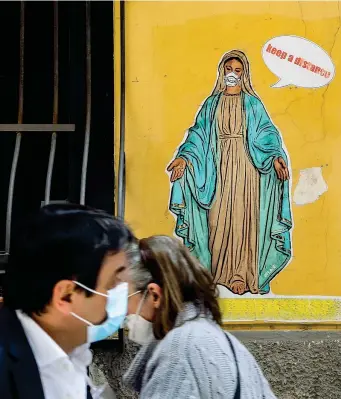  ?? (Foto Carlo Hermann / AFP) ?? Murales
A Napoli il disegno di un writer raffigura una vergine con tanto di mascherina. Il messaggio ai passanti è chiaro. Dice, in inglese: «Tenete le distanze»