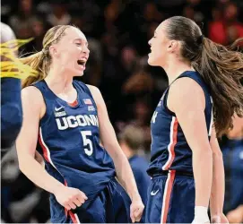  ?? Greg Fiume/Getty Images ?? Paige Bueckers (5) and Nika Mühl (10) of the UConn Huskies celebrate in the second quarter against the Georgetown Hoyas at Entertainm­ent & Sports Arena on Sunday in Washington.