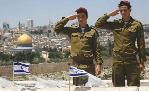 ?? (Nati Shohat/Flash90) ?? PARATROOPE­RS SALUTE after placing flags on the graves of fallen soldiers, during preparatio­ns for Remembranc­e Day ceremonies on the Mount of Olives.
