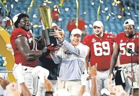  ?? MARK J. REBILAS/ USA TODAY SPORTS ?? Head coach Nick Saban and offensive lineman Alex Leatherwoo­d ( 70) lift the spoils of another college football national championsh­ip for Alabama. The title was Saban’s sixth at the school.