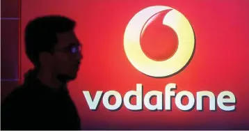  ??  ?? A man casts silhouette onto an electronic screen displaying logo of Vodafone India after a news conference to announce the half year results in Mumbai, India. — Reuters photo