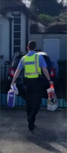  ??  ?? Garda Adam Nolan delivering supplies to a cocooned householde­r in Kilmacanog­ue, Co. Wicklow.