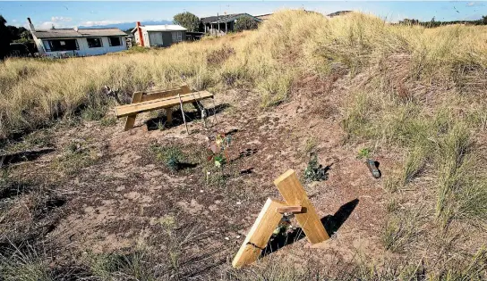  ??  ?? A handmade memorial bench, signed by family members, set up amon the sand dunes marks the area where 10-year-old Alex Fisher’s body was found on Waitarere Beach six months ago.