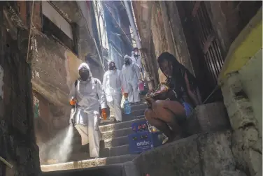  ?? Bruna Prado / Associated Press ?? Volunteers spray disinfecta­nt in an alley to help contain the spread of the coronaviru­s in Rio de Janeiro. The group said Saturday was the final day of its service as funding for materials had run out.