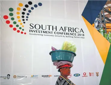  ?? Picture: Alaister Russell ?? A street vendor balances her goods on her head as she makes her way past the Sandton Convention Centre in Johannesbu­rg on Friday during the South Africa Investment Conference.