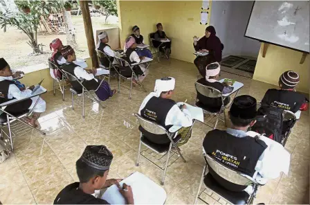  ??  ?? Life lessons: Pupils attending a class at the Al-Hidayah Islamic boarding school in Sei Mencirim. — AP