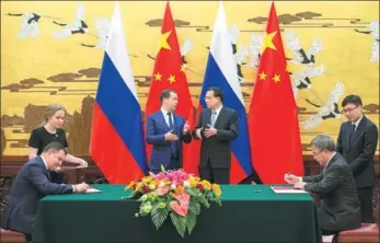  ?? KUANG LINHUA / CHINA DAILY ?? Premier Li Keqiang and Russian Prime Minister Dmitry Medvedev converse while witnessing the signing of several cooperatio­n documents on Wednesday in Beijing.