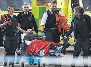  ??  ?? Above, a victim is treated by emergency services near Westminste­r Bridge. Below, a police officer aids an injured man