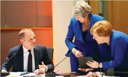  ??  ?? Britain's Prime Minister Theresa May and Germany's Chancellor Angela Merkel look at a tablet next to European Council President Donald Tusk, ahead of a European Council meeting on Brexit at the Europa Building at the European Parliament in Brussels, Belgium April 10, 2019. Kenzo Tribouilla­rd/Pool via Reuters