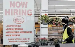 ?? NAM Y. HUH/AP ?? A man pushes carts by a hiring sign at a Jewel Osco grocery store in April in Deerfield, Ill.