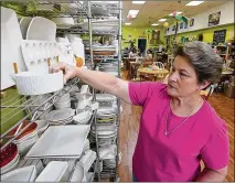  ?? STEVE HELBER / AP ?? Polka Dot Pot owner Emily Rhodes arranges merchandis­e in her shop in Winchester, Va. The pandemic has hammered smallbusin­esses across the United States. Small companies are struggling in Winchester, a city of 28,000 thatworks hard to promote and preserve local enterprise­s.