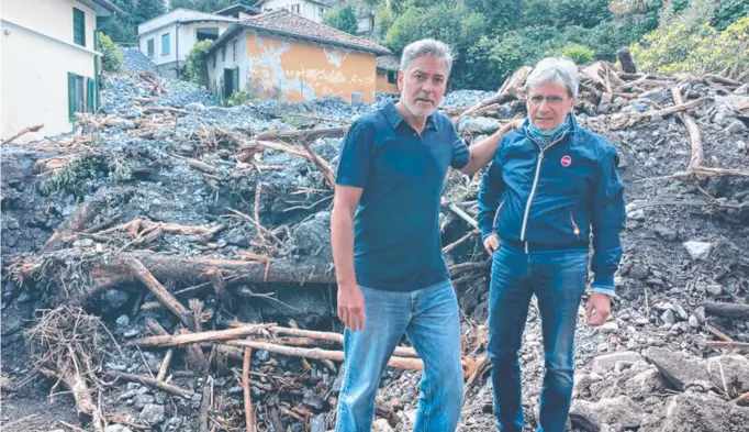  ??  ?? George Clooney helps the mayor of Laglio, Roberto Pozzi, clean up the devastated Italian town after flash flooding caused mayhem and trapped the star in his Lake Como mansion.