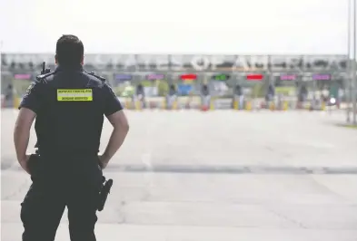  ?? CHRISTINNE MUSCHI / BLOOMBERG ?? A Canadian border agent stands guard at the Canada-U.S. border in Saint-Bernard-de-Lacolle, Que. This plague
is demonstrab­ly manageable without shutting down borders at the drop of a hat, Chris Selley writes.