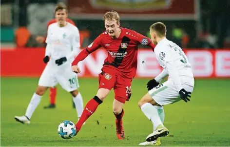  ?? FOTO: REUTERS ?? Leverkusen­s Doppel-Torschütze Julian Brandt versetzt Maximilian Eggestein (rechts). Im Hintergrun­d Max Kruse, der Bremens Führungsto­r erzielt hatte.