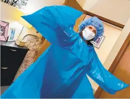  ?? LEADINGAGE VIA NYT ?? A health care worker shows a blue gown with no openings for hands that was delivered to a nursing home in Seattle.