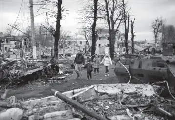  ?? FELIPE DANA/AP ?? A family walks on a road clogged by destroyed Russian tanks last Wednesday in Bucha, Ukraine, near Kyiv.