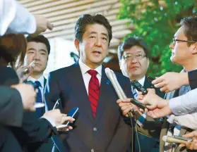  ?? KYODO NEWS VIA AP ?? REACTION. Japanese Prime Minister Shinzo Abe, center, answers a reporter’s question about North Korea’s missile launch, at his official residence in Tokyo.