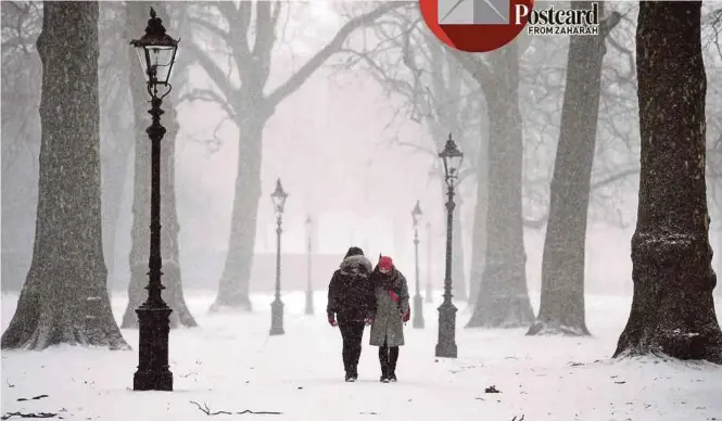  ?? EPA PIC ?? Snow falling as a couple walk through Green Park in London, the United Kingdom, on Friday. The extreme weather has badly affected the city’s undergroun­d transporta­tion system.