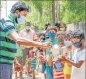  ?? PTI ?? An NGO worker distribute­s milk among children at a village during a nationwide lockdown in the wake of coronaviru­s pandemic in Santipur, West Bengal, on Saturday.