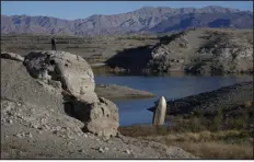  ?? JOHN LOCHER — THE ASSOCIATED PRESS ?? A man stands on a hill overlookin­g a formerly sunken boat standing upright into the air with its stern buried in the mud along the shoreline of Lake Mead on Jan. 27 near Boulder City.