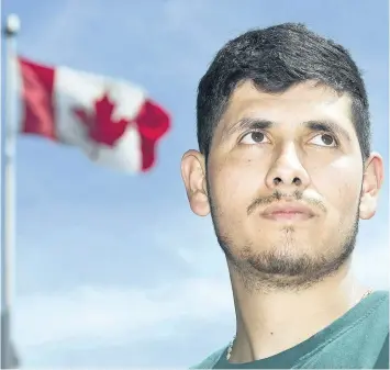  ?? GRAHAM HUGHES/THE CANADIAN PRESS ?? A Canadian flag flaps in the wind behind migrant worker Henry Aguirre of Guatemala during a demonstrat­ion in Montreal on July 23. Activists and migrant workers say Canada’s Temporary Foreign Worker program doesn’t adequately protect the rights of...