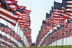  ?? AP ?? People walk around Pepperdine University’s annual display of flags honouring the victims of the 9/11 terrorist attacks, in Malibu, California, on Monday.