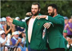  ?? (AFP/Reuters) Scheffler is presented with the Green Jacket by ?? Scottie Scheffler of the US poses with the trophy after winning the 2024 Masters at Augusta National Golf Club in Augusta, Georgia. Right: last year’s winner Spain’s Jon Rahm.